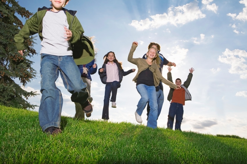 Children running down a grassy hill